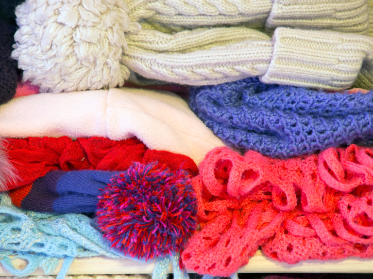 A closeup of a stack of winter hats and scarves