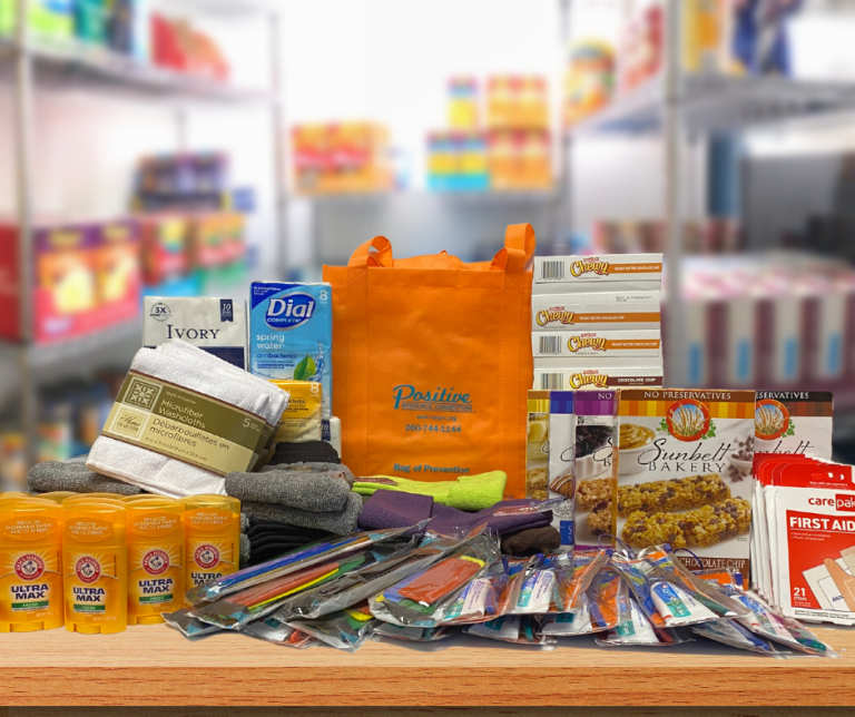 Bag of Prevention with donated items in front of a blurred background image of the PRC food pantry