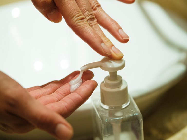 Closeup of hands getting soap from a soap dispenser.