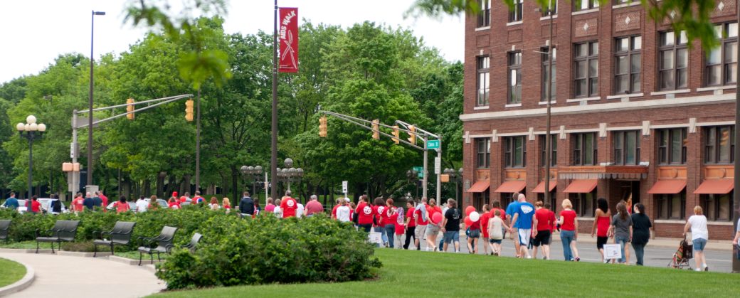 Distant view of a line of people walking downtown wearing matching red shirts