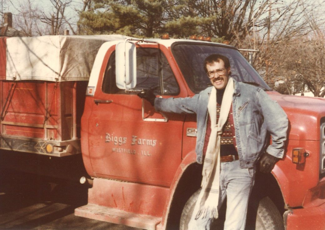 Gregory Manifold smiling and standing in front of a red truck