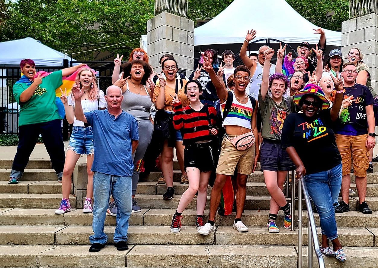 Group photo of happy cheering people wearing Pride gear at Fort Wayne Pride