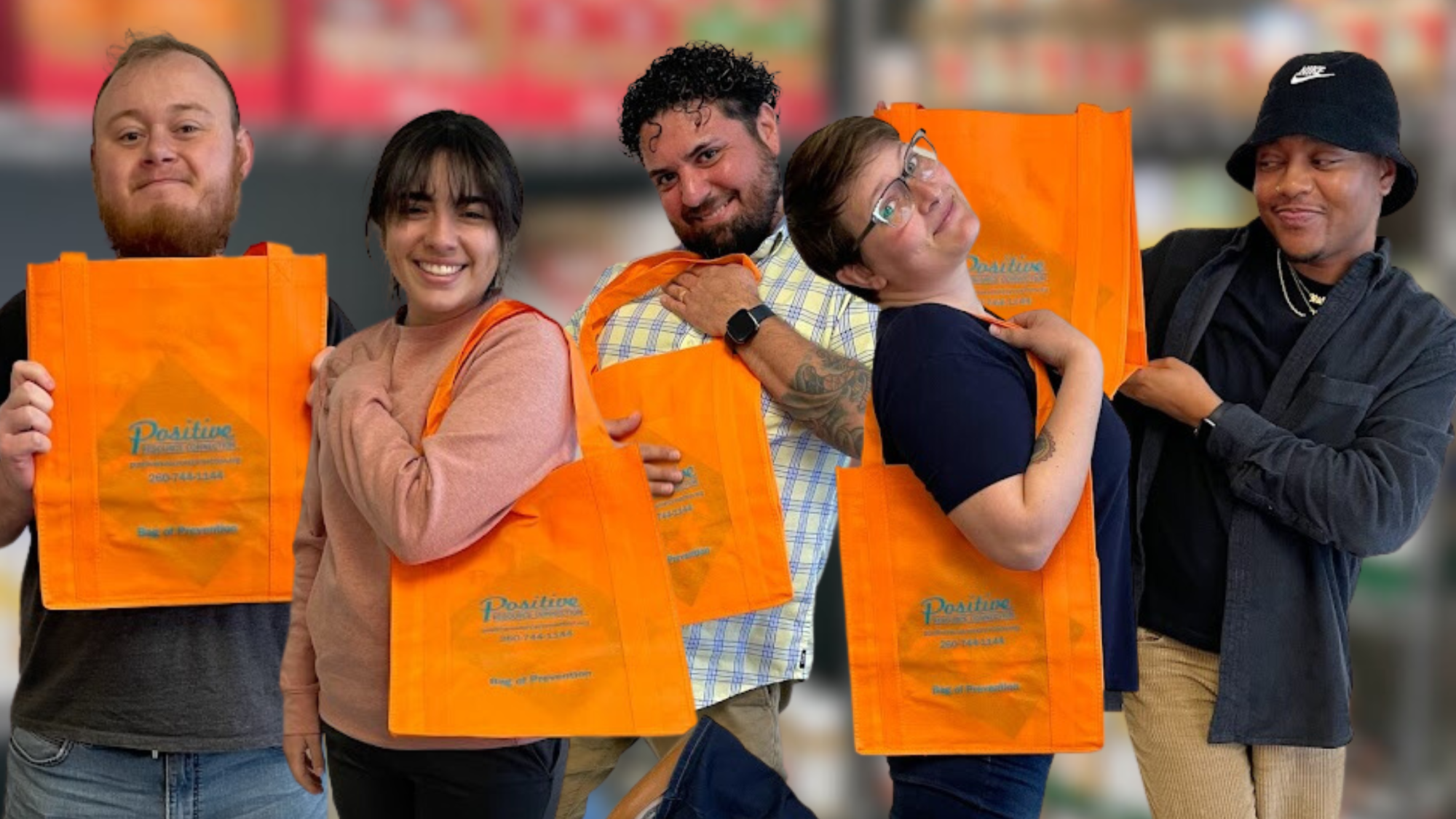 Some PRC staff members smiling and holding orange tote bags with the PRC logo