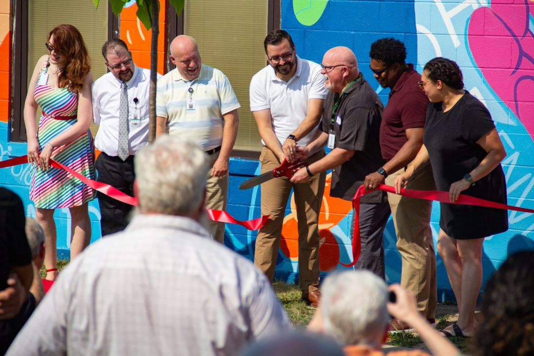 Group cuts red ribbon with large scissors