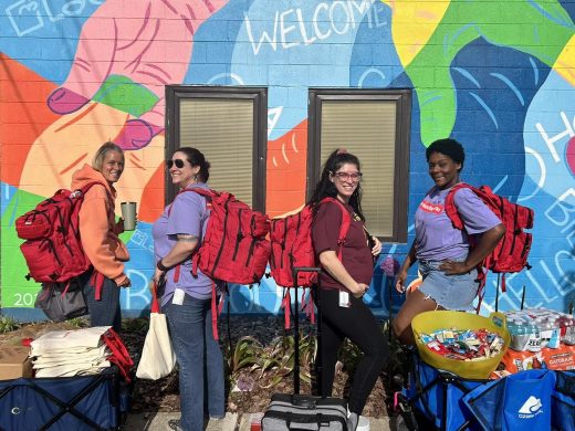 PRC Street Outreach team with red backpacks standing in front of mural