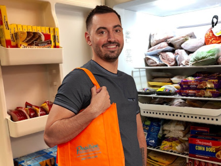 PRC team member holds orange tote by client freezer
