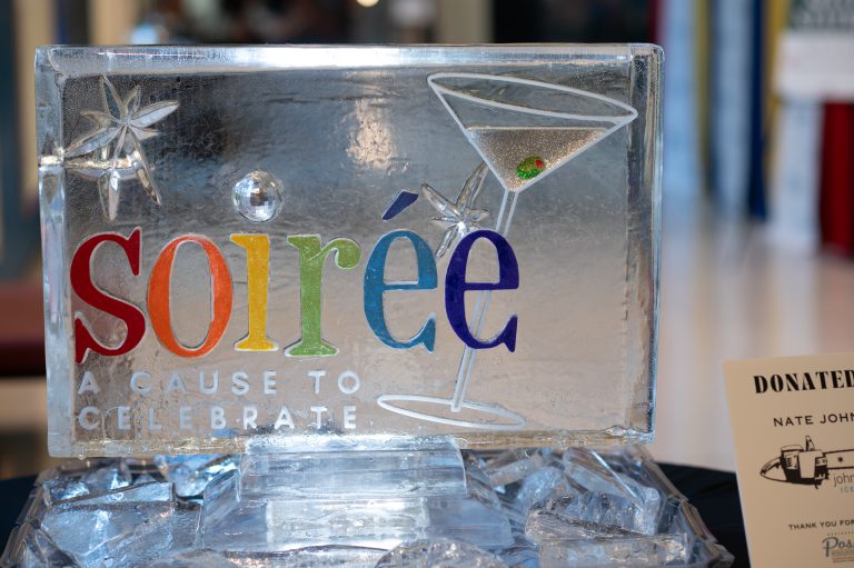 Ice sculpture with rainbow text "Soiree" and martini glass